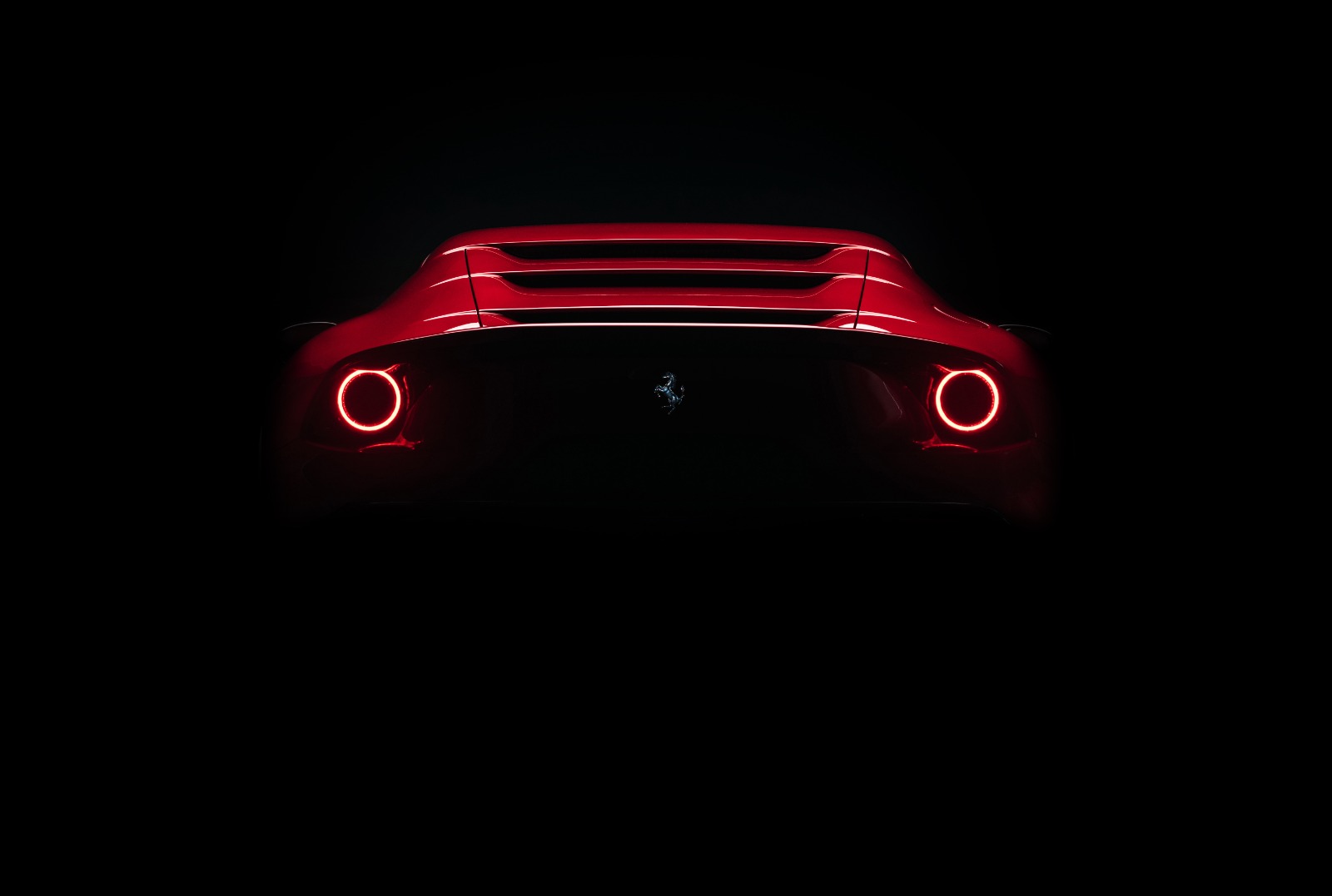 Ferrari rouge vue arriere avec feux ronds sur fond noir